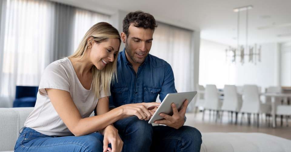 happy-couple-using-a-tablet-computer-at-home-automation-concept